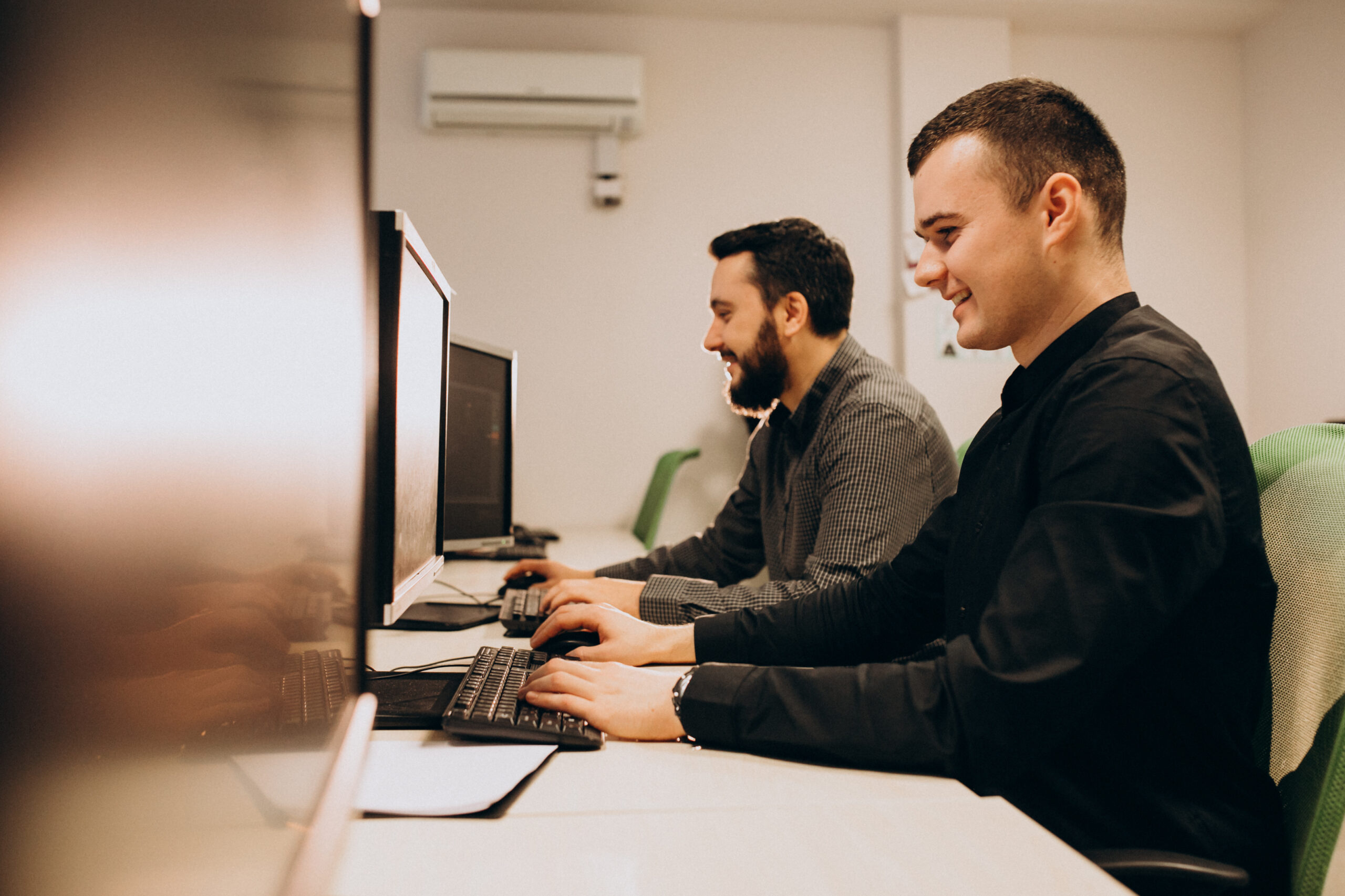 dois desenvolvedores web trabalhando com integrações SAP em seus computadores em uma sala de trabalho